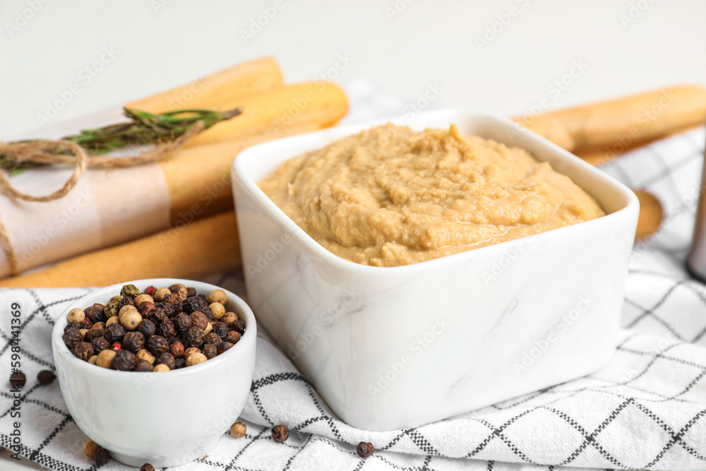 Bowl with tasty hummus on light background, closeup