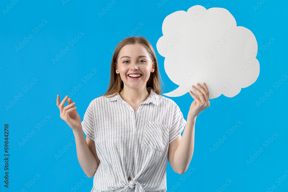 Happy young woman with blank speech bubble on blue background