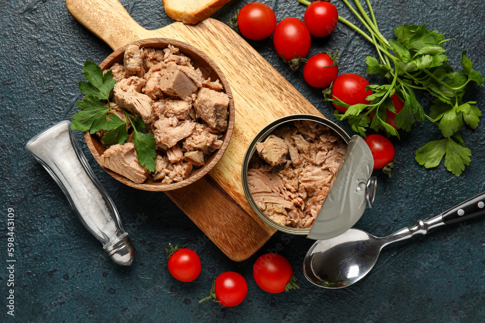 Composition with delicious canned tuna, tomatoes and fresh herbs on dark table