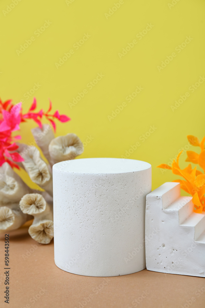 Decorative plaster podiums, coral and seaweed on yellow background