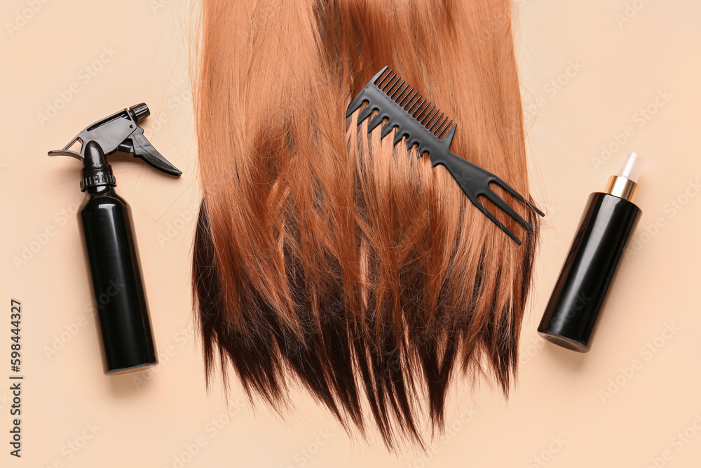 Beautiful hair with comb and sprays on beige background