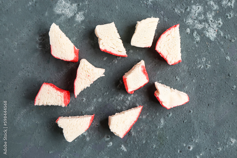 Pieces of tasty crab sticks on green background