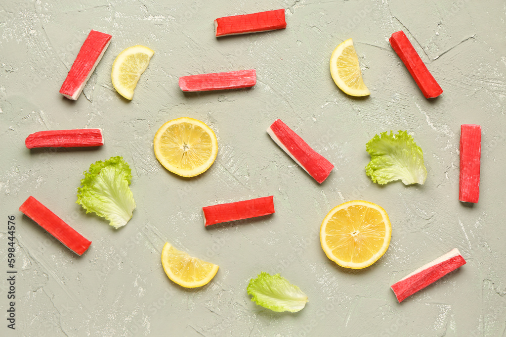 Tasty crab sticks, slices of lemon and lettuce on light background