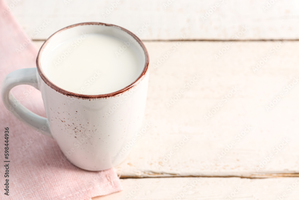 Cup with fresh milk on white wooden table