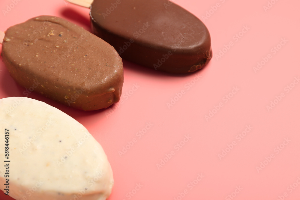 Different chocolate covered ice cream on stick against pink background, closeup