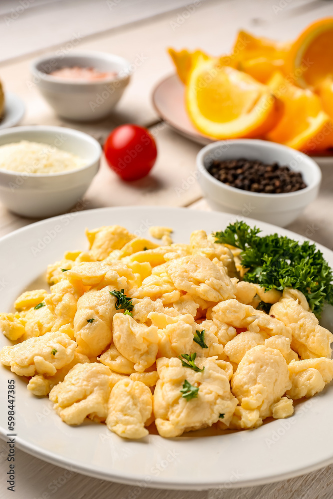 Plate of delicious scrambled eggs with ingredients on  white wooden background