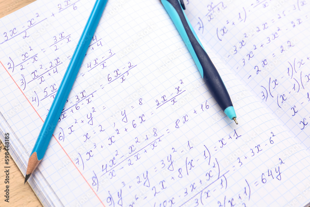 Copybook with maths formulas, pen and pencil, closeup