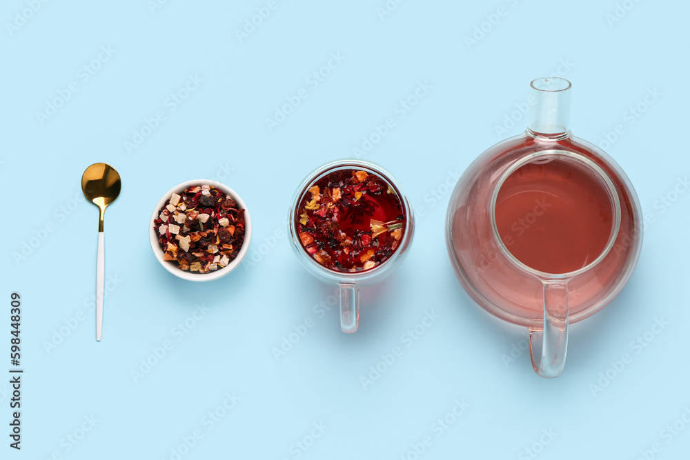 Teapot with cup of tea and dried fruits on blue background