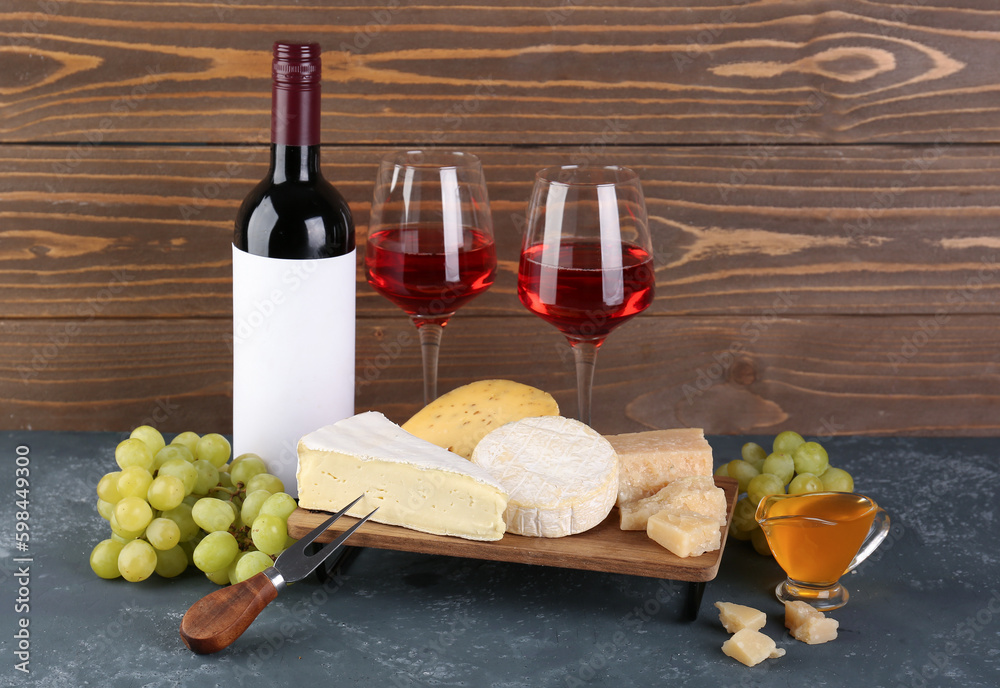 Different types of cheese, bottle and glasses with wine on table