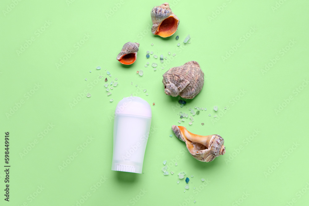 Deodorant with shells and sea salt on light green background