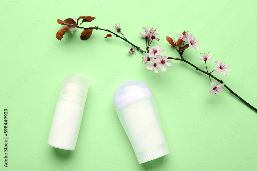 Deodorants with blooming branch on light green background