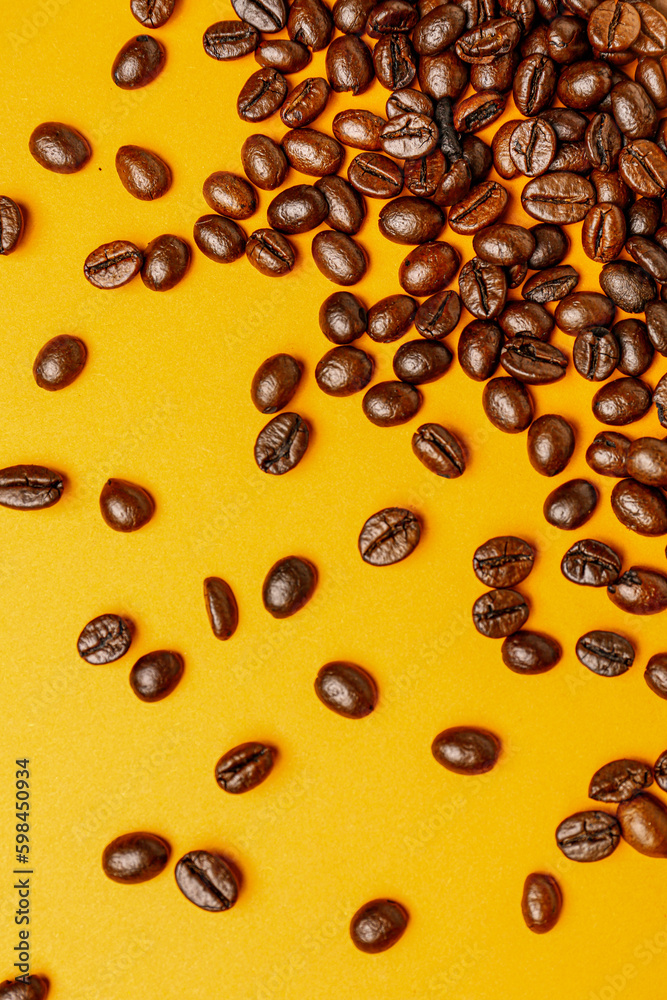 Scattered coffee beans on orange background