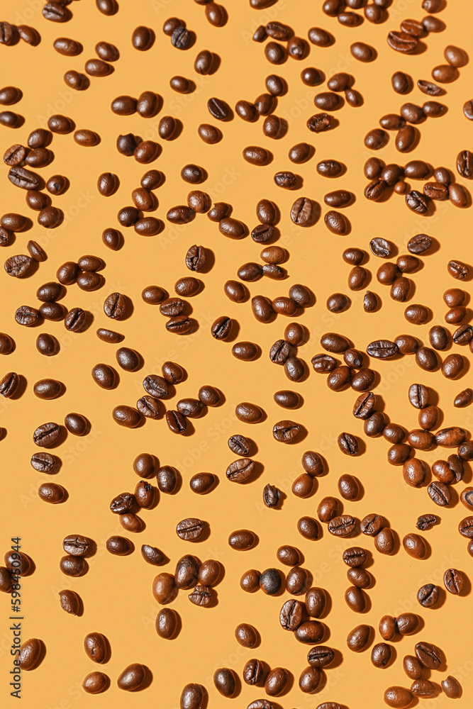 Scattered coffee beans on orange background