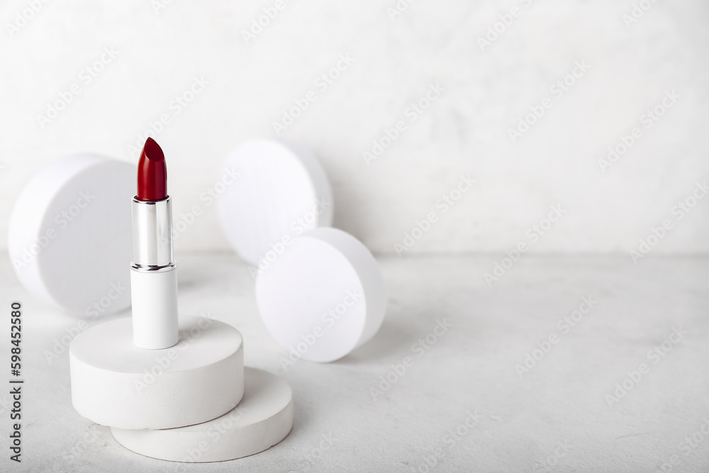 Decorative plaster podiums and lipstick on light background