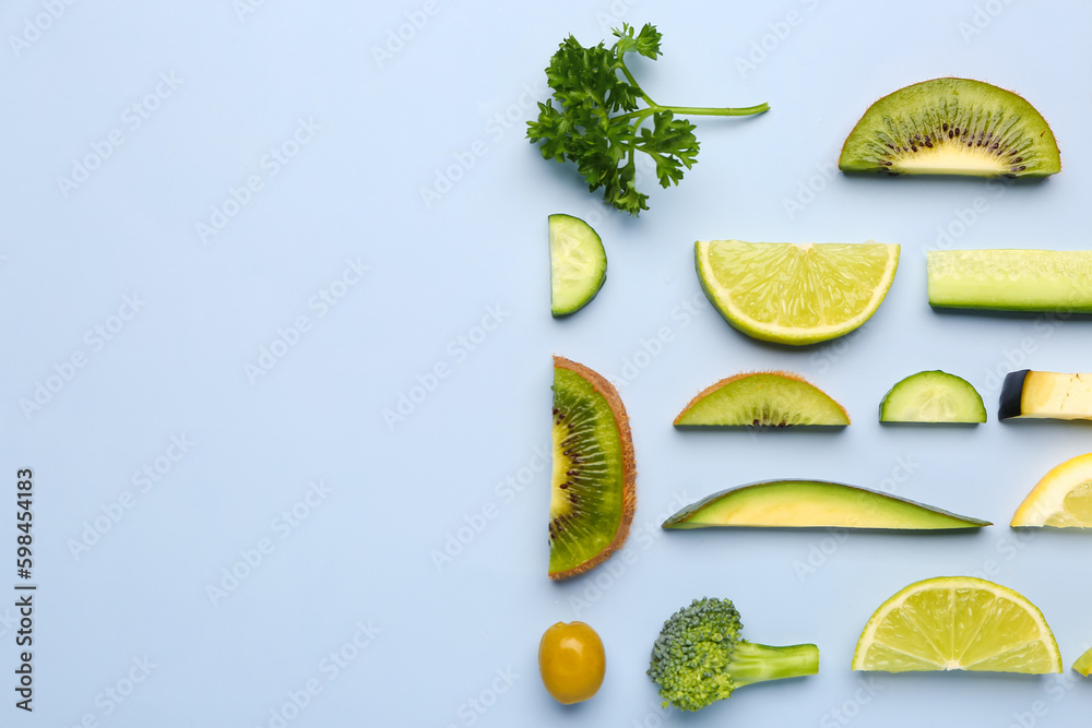 Composition with green fresh fruits and vegetables on blue background