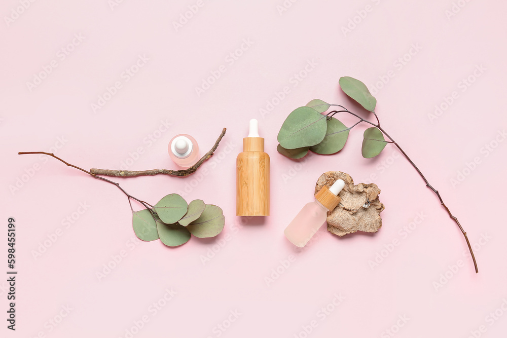 Bottles with cosmetic oil and eucalyptus branch on pink background