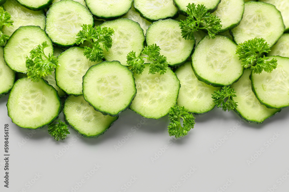 Slices of cucumber with parsley on grey background