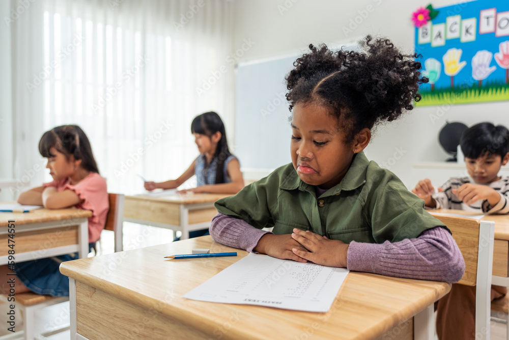 African American student doing exam in classroom at elementary school. 