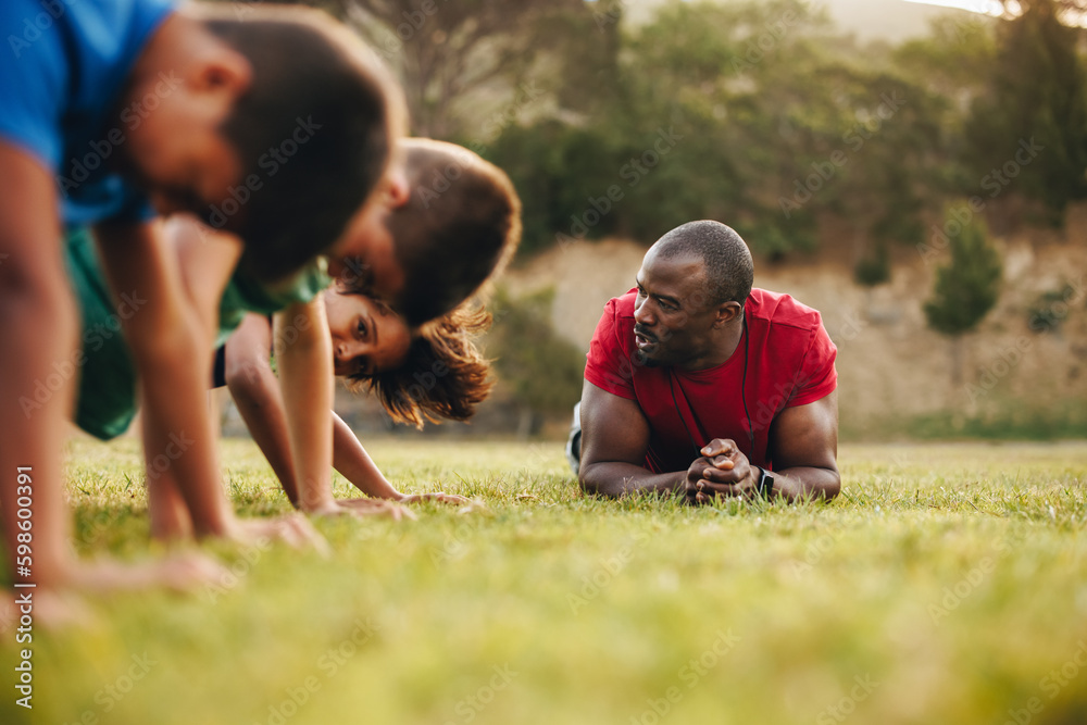 Sports coach training a school team in a rugby field