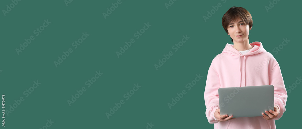 Teenage boy with laptop on green background with space for text