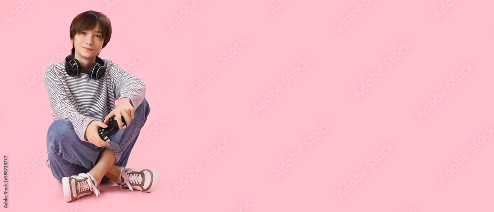 Teenage boy with headphones and controller for playing video games on pink background with space for