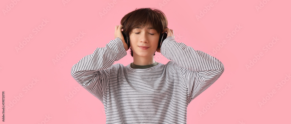 Teenage boy in headphones listening to music on pink background