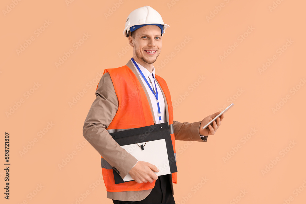 Male architect with tablet computer on beige background