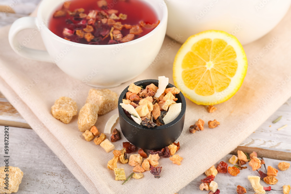 Bowl with dried fruit mix and cup of tea on white wooden table, closeup