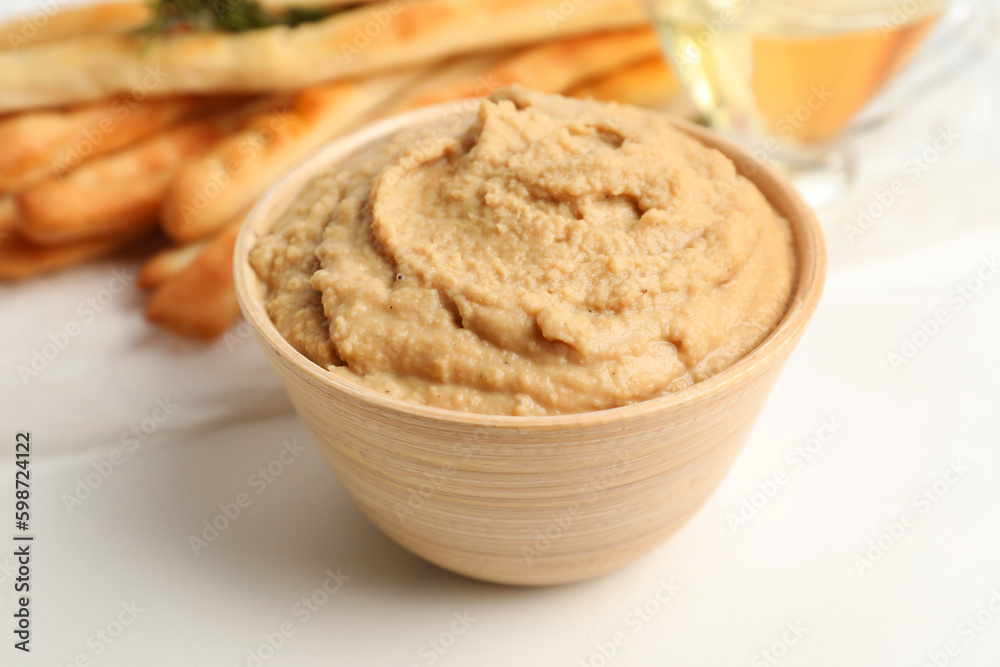 Bowl with tasty hummus on light background, closeup