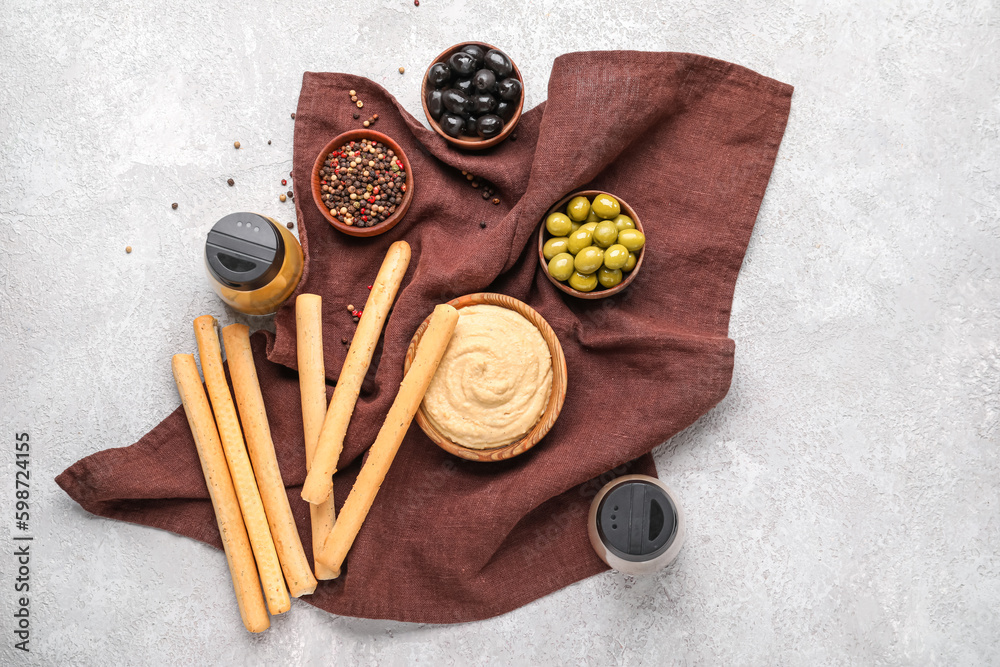 Tasty Italian Grissini, bowl with hummus and ingredients on light background