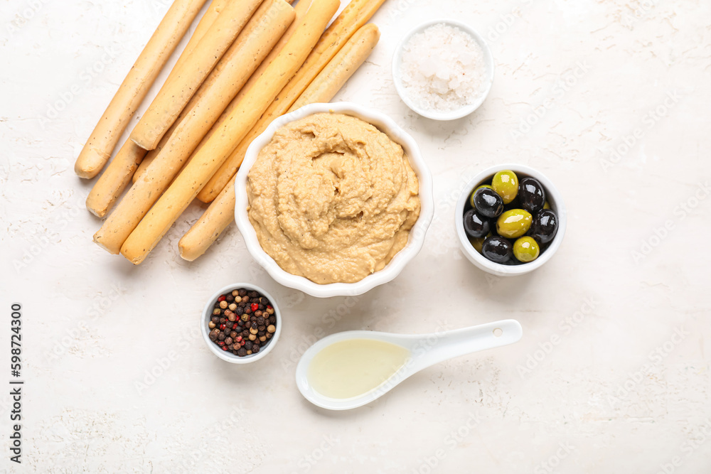 Bowl with tasty hummus and Italian Grissini on light background