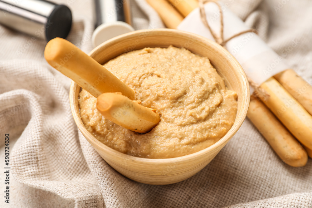 Bowl with tasty hummus and Italian Grissini on table, closeup