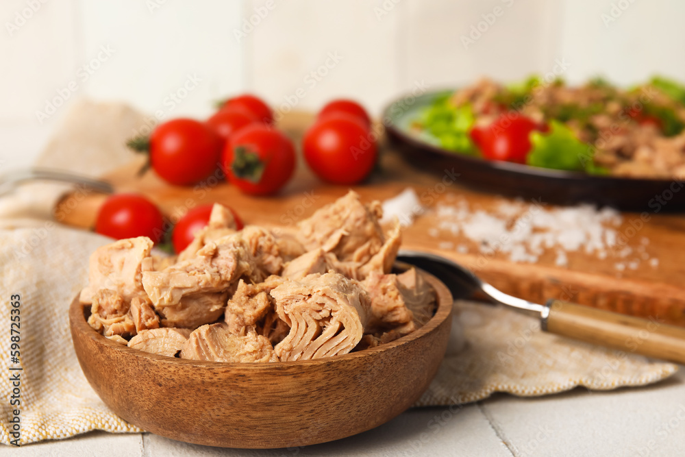 Wooden bowl with delicious canned tuna on white tiled table