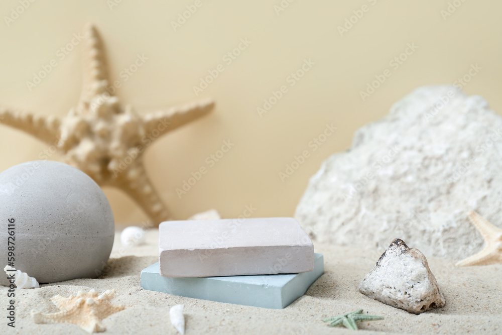 Decorative plaster podiums in sand on light background