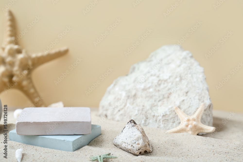 Decorative plaster podiums in sand on light background