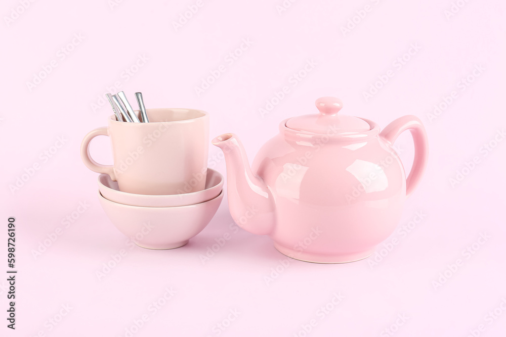 Teapot, bowls and mug with spoons on lilac background