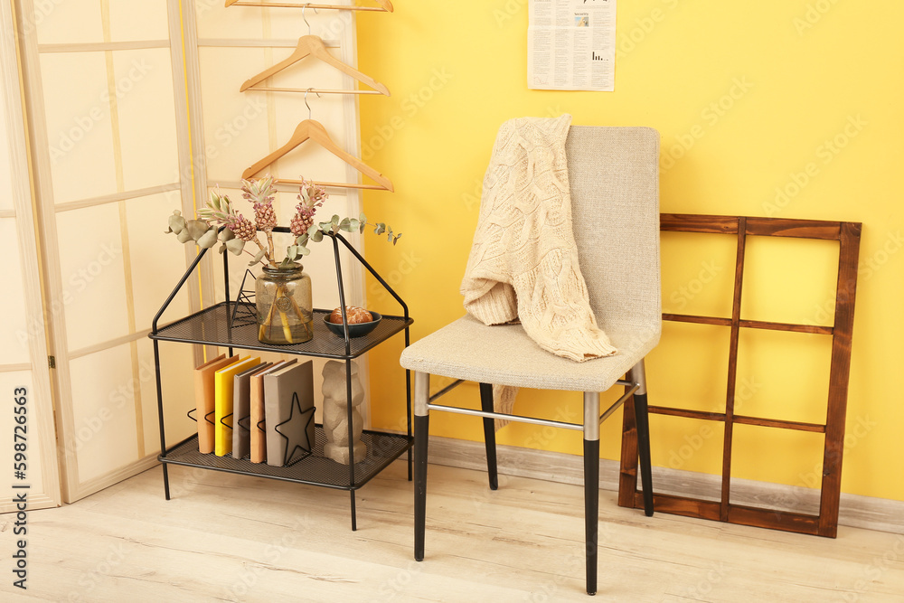 Interior of stylish room with shelving unit, chair and folding screen