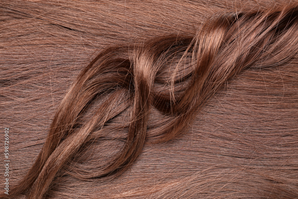 Curled and straight brown hair as background, closeup