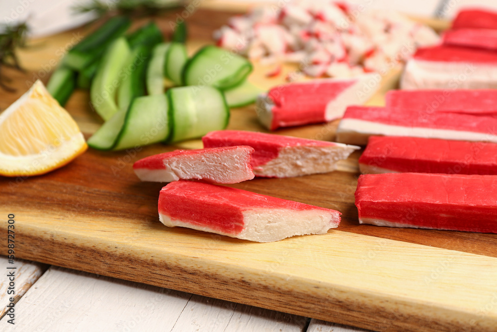 Wooden board with tasty crab sticks on table, closeup