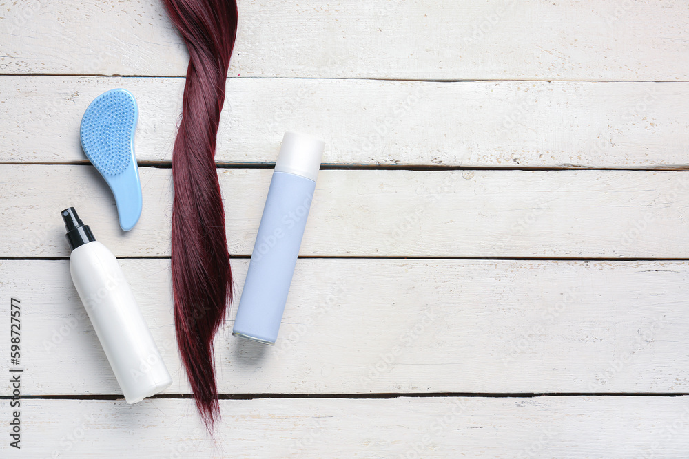 Red brown hair with brush and sprays on white wooden background