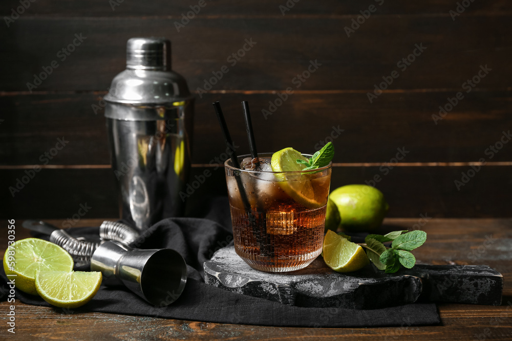 Glass of tasty Cuba Libre cocktail on dark wooden background