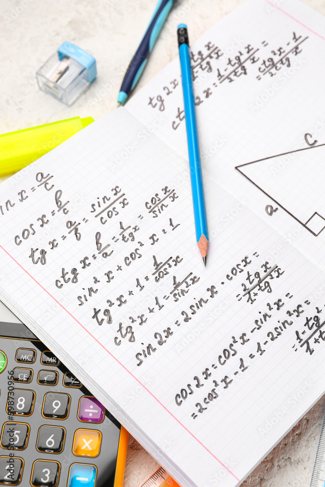 Copybook with maths formulas and pen, closeup