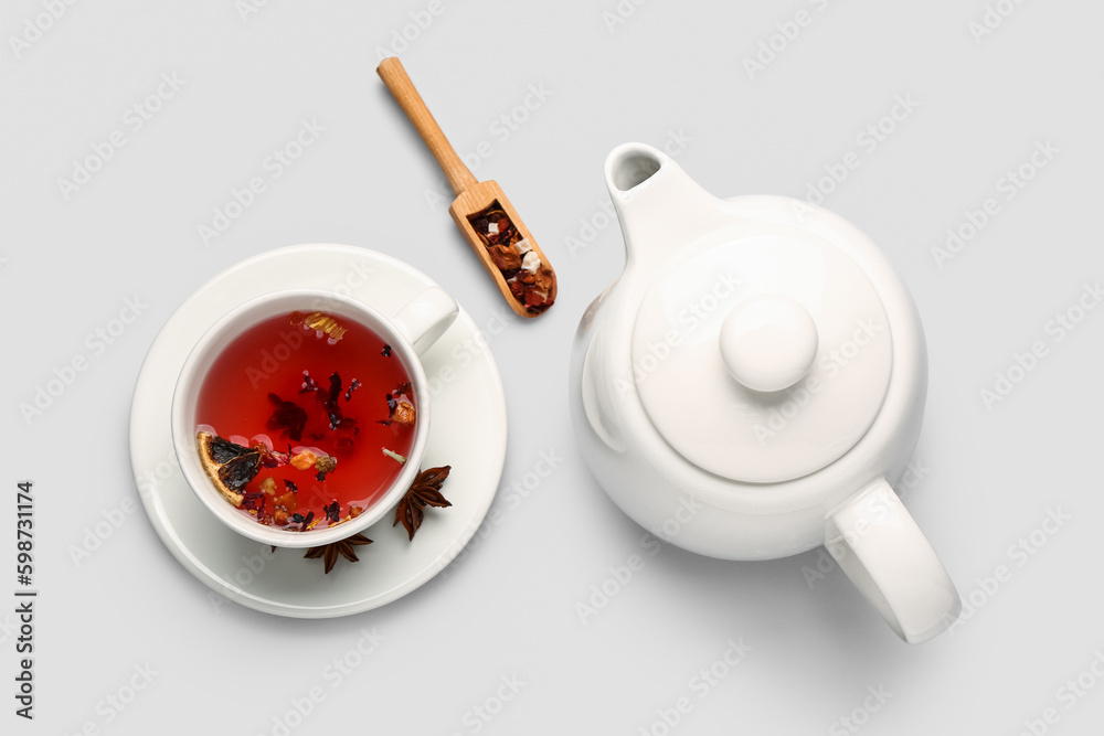 Ceramic teapot with cup of fruit tea on grey background