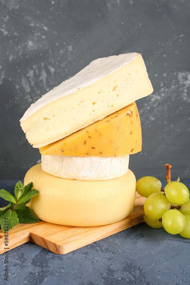 Wooden board with different types of cheese on table