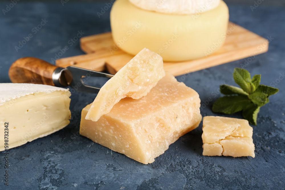 Pieces of tasty cheese on blue background, closeup