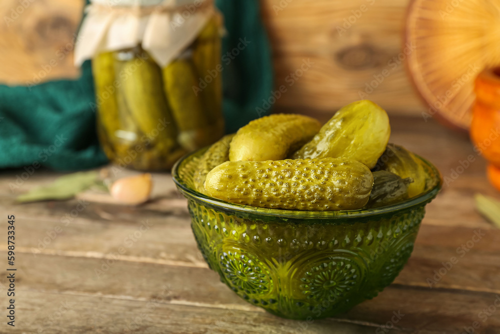 Bowl with tasty canned cucumbers on wooden table