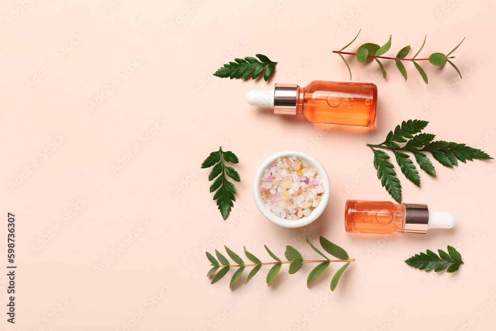 Bottles of cosmetic oil with plant twigs and sea salt on beige background