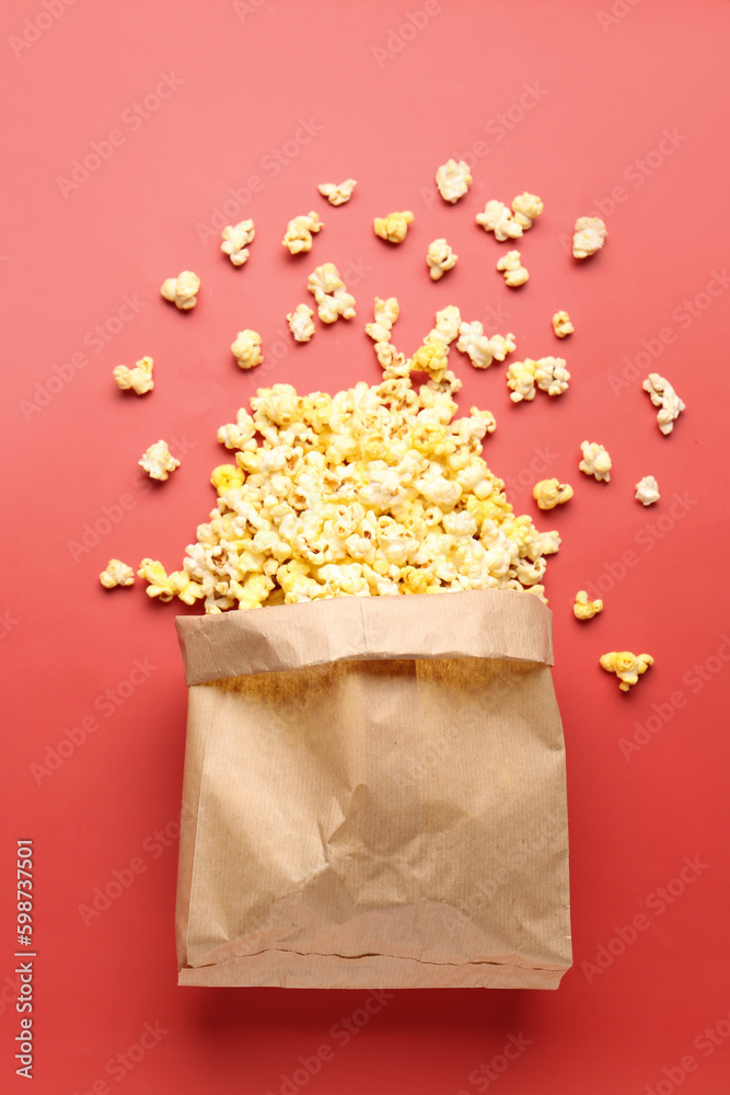 Paper bag with crispy popcorn on red background