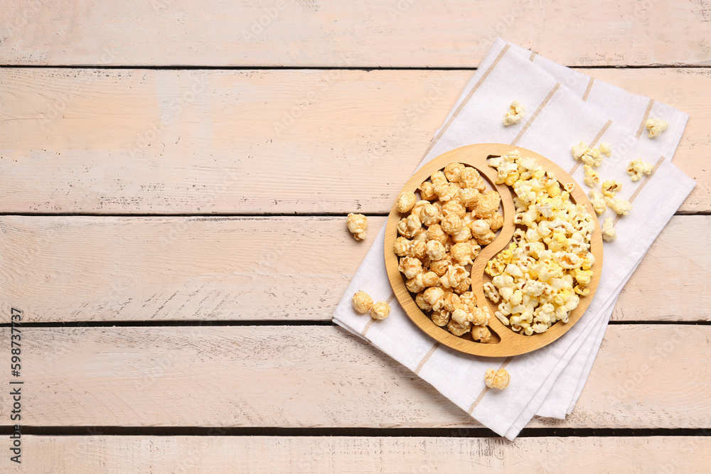 Plate with crispy popcorn on white wooden background