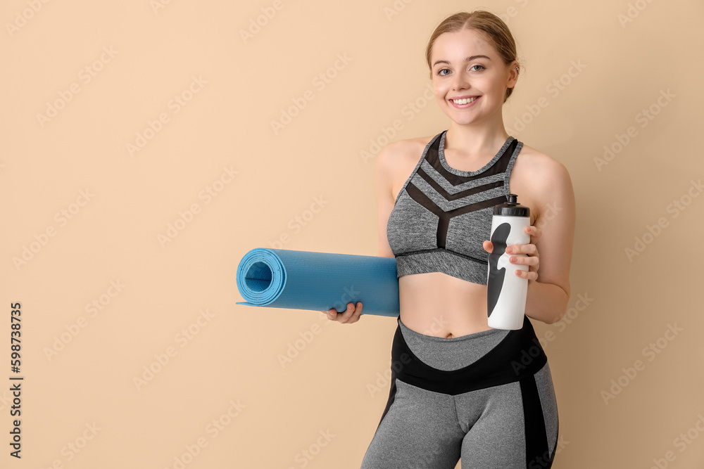 Sporty young woman with yoga mat and bottle of water on beige background